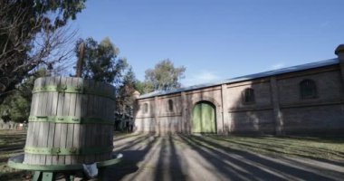 Seyahat ve panning kamera hareket vasıl günbatımı altın saat büyük tuğla inşaat mükemmel. eski vintage ahşap varil. Ağaçlar, yapraklar ve çim. Kiler Mendoza, Arjantin şarap üretimi için.