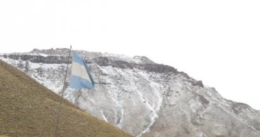 Arjantinli akan ve bankamatik kar ile dağlar rüzgarlı bir gri bulutlu gün hareketli bayrak yıpranmış. Mendoza, Arjantin.