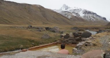 Doğal sağlıklı sıcak termal dış Cajon bulutlu bir günde kışın Andes Campanario dağ kar ile izlerken Grande banyo genç adam. Mendoza Cuyo, Arjantin.