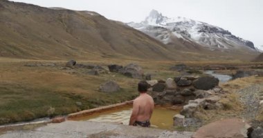 Doğal sağlıklı sıcak termal dış Cajon bulutlu bir günde kışın Andes Campanario dağ kar ile izlerken Grande banyo genç adam. Mendoza Cuyo, Arjantin.