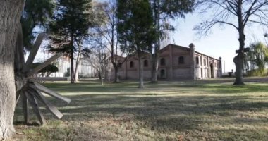 Seyahat ve panning kamera hareket vasıl günbatımı altın saat büyük tuğla inşaat mükemmel. Eski ahşap vintage sepeti Vagon tekerlek. Ağaçlar, yapraklar ve çim. Kiler Mendoza, Arjantin şarap üretimi için.