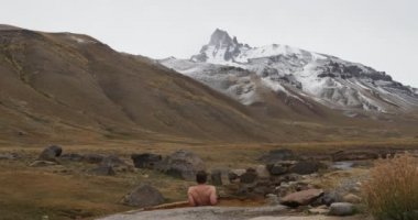 Doğal sağlıklı sıcak termal dış Cajon bulutlu bir günde kışın Andes Campanario dağ kar ile izlerken Grande banyo genç adam. Mendoza Cuyo, Arjantin.