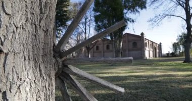 Seyahat ve panning kamera hareket vasıl günbatımı altın saat büyük tuğla inşaat mükemmel. Eski ahşap vintage sepeti Vagon tekerlek. Ağaçlar, yapraklar ve çim. Kiler Mendoza, Arjantin şarap üretimi için.