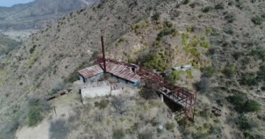Hava dron sahne. Teleferik Chilecito - La Mejicana altın madeni'üçüncü istasyonu. İnşaat, demir raylar, paslı vagonlar genel görünümü sahnede. Kamera hareketleri uzakta artan. Arka plan, dağlar