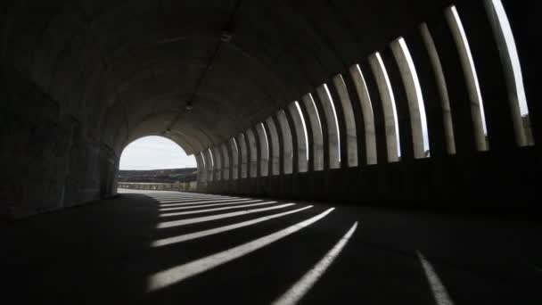 Hand held camera walking through and getting out a brutalist concrete tunnel. Lights and shadows rithms made by windows, openings, within the tunnel. Street infraestructure. Argentina, Mendoza — Stock Video