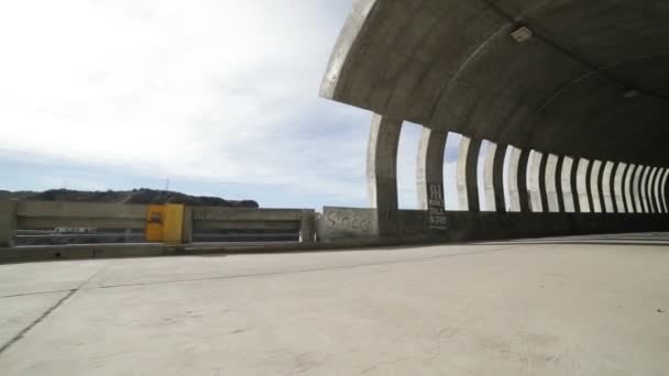 Hand-het gehouden camera naar te lopen en krijgen in een brutalist concrete tunnel. Licht en schaduwen rithms gemaakt door windows, openingen, binnen de tunnel. Straat infraestructure. Mendoza, Argentinië — Stockvideo