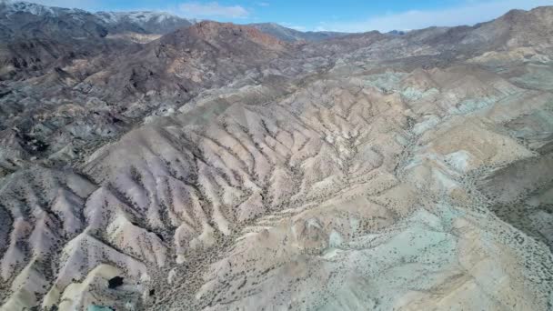 Escena aérea de drones de coloridas montañas arenosas y rocosas erosionadas. Recorriendo formaciones muy altas en el cielo, ríos secos, vegetación y colores en el paisaje. Argentina . — Vídeos de Stock