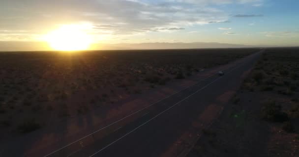 Antenn drönare scen av van med trailer hus på linjen, på National Park Talampaya, La Rioja, Cuyo Argentina. Solnedgången gyllene timme. Solen vid horisonten. Berg på bakgrunden landskap. — Stockvideo