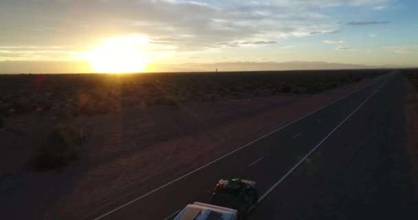 Aerial drone scene of van with trailer house on the route, at National Park Talampaya , La Rioja, Cuyo Argentina. Sunset golden hour. Sun on the horizon. Mountains on background landscape. — Stock Video