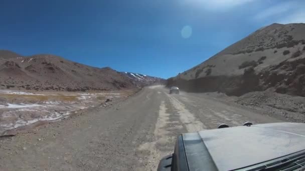 在沙漠 雪山之间的德萨瓜德罗河旁 带着四轮驱动面包车在砾石路上行驶 车的钩子游览安第斯山脉的布拉瓦泻湖 里奥哈 — 图库视频影像