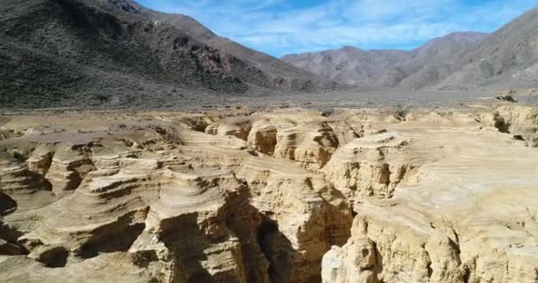 Antenowe drone sceny Ocre kanionu w żółtej rzeki i góry Famatina. Kamera porusza się do przodu nad erozji piaskowca, z klifów, warstwy, kanały ściekowe, erozji krajobraz. La rioja, Argentyna — Wideo stockowe