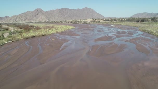 空中ドローン シーン Fiambala 蛇行の砂川や森の中 カメラを越え水昇順と砂丘 バック グラウンドでロッキー山脈を乾燥します アルゼンチンのカタマルカ — ストック動画