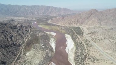 Genel görünümü geniş Fiambala nehir manzara kıvrımlı ve kuru rocky Dağları ile hava dron sahne. Kum tepeleri ve yol Seyahat Otobüs. Yukarıda nehir yüksek irtifada uçan