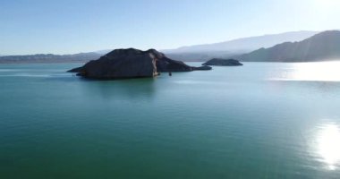 Günbatımı gölde sahnenin ortasında rock Adaları ile hava dron sahne. Kayalar yaklaşan su üzerinde uçan. Mercek Parlaması, ses ışık, ışık sızıntısı ve yansıma. Cuesta del Viento Barajı