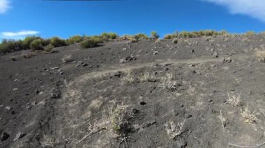 Volkanik toprak, enkaz, malacara yanardağ doğru üzerinde yürüme. Çakıl iz ile seyahat. Arka plan dağ. Mendoza, Arjantin.