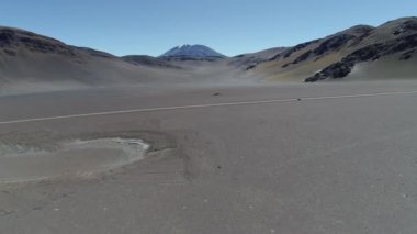 Desertic peyzaj dağlar ve volkan ile hava dron sahne. Kayalık kuru iklim tarafından yol geçiş ile. İleri uçan.