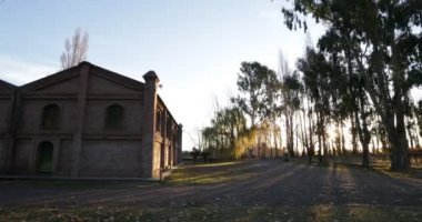 Kırsal yarda günbatımı gösteren kiler tuğla yapımı üzerinde yürüme. Bitki örtüsü ile backlight birim ışık yapma Güneş'ten. İçecek endüstrisi. Mendoza, Arjantin