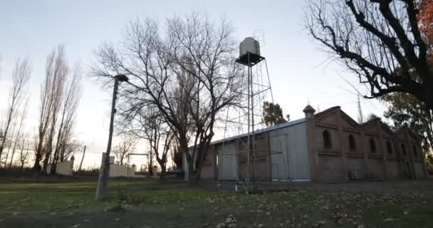 Caméra à main dans la ferme approchant réservoir d'eau surélevé. Contexte de l'entrepôt de briques. Mendoza, Argentine 