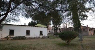 Kırsal İnşaat bahçede yürüyüş. Arka plan açık ve tuğla inşaat İspanyol sömürge evinde. El kamera.