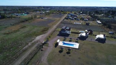 Hava dron sahne, şehir banliyölerinde özel kentleşme. Havuzu, saman şemsiye ve plaj sandalyeleri ile eğlence parkı. Aynı ev, diğer urbanizations ve üzüm bağları, arka plan. Kamera iner