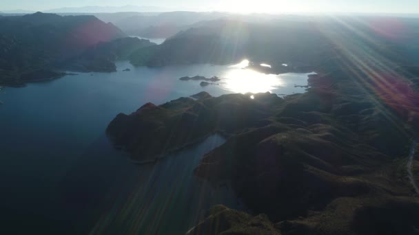 日落时山间巨大湖泊的空中无人机场景 耀斑和体积灯 在水面上飞得很高 雷尤诺斯水电大坝 背景山的自然的 Silhuettes — 图库视频影像