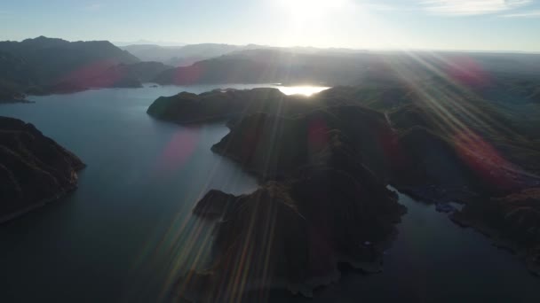 日落时山间巨大湖泊的空中无人机场景 耀斑和体积灯 在水面上向后飞行 门多萨的雷尤诺斯水电站大坝 背景山的自然的筒水 — 图库视频影像
