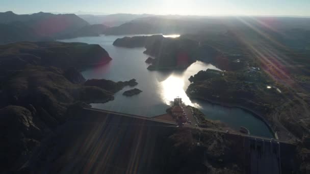 日落时山间巨大湖泊的空中无人机场景 耀斑和体积灯 在水面上飞得很高 阿根廷门多萨的雷尤诺斯水电站大坝 背景山的自然的 Silhuettes — 图库视频影像
