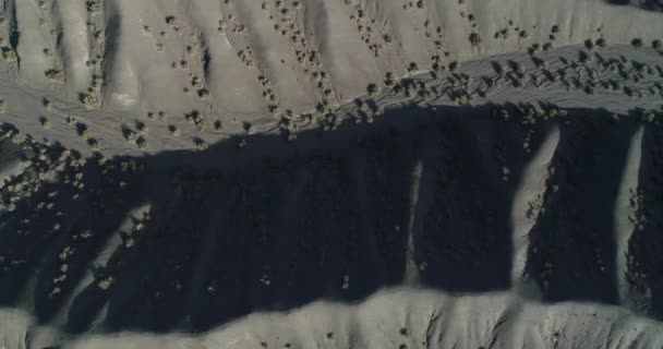 Luchtfoto senital drone scène bij zonsondergang van geërodeerde heuvels en rivieren van desertic ambient droog. Detail van colorfull aarde en tekening van watererosie op het landschap. San Juan, Calingasta — Stockvideo