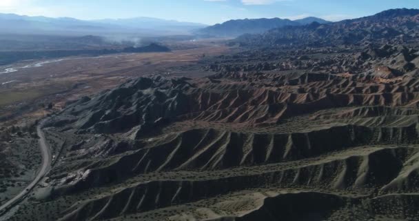 El Leoncito 川流域の空中ドローン シーン。神秘的な風景は、黒、茶色とオレンジ色の浸食された山々、オレンジ川のベンドで構成されます。Calingasta、サン ・ フアン州、アルゼンチン — ストック動画