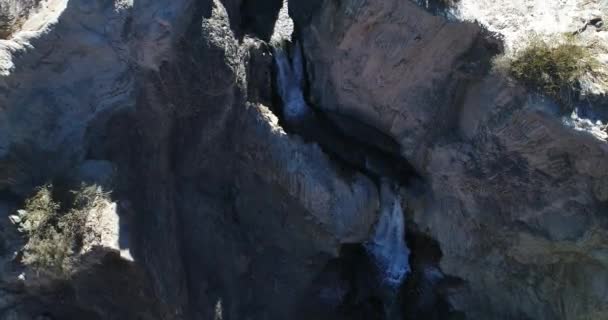 Aerial drone scene from senital to front view, from top view of two waterfall bewteen rocks and cliffs to general view of dry valley. Flares, volume light during scene. National Park El Leoncito — Stock Video