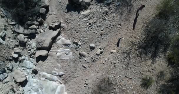 Escena aérea sensual de un niño jugando en un paisaje rocoso seco. La cámara se acerca al bebé. Saco de tierra desértico, explorando el aprendizaje de la naturaleza. Huaco, provincia de San Juan, Argentina — Vídeos de Stock