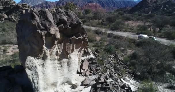 Воздушные сенитальные беспилотники летают вокруг скальных образований, которые выходят из земли под углом. Фон сложенных гор. Провинция Сан-Хуан, Уако, Аргентина — стоковое видео
