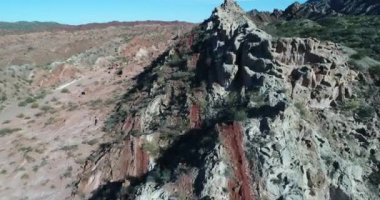 Renkli katlanmış dağlar hava dron sahne. Kırmızı ve beyaz toprak ve taş yapıları üzerinde uçan. San Juan Eyaleti, Huaco, Arjantin