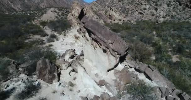 Antena senital drone sceny latają formacje skalne, które wyłaniają się z ziemi, z kąta. Na tle gór po złożeniu. Rodzimej roślinności San Juan province, Huaco, Argentyna — Wideo stockowe