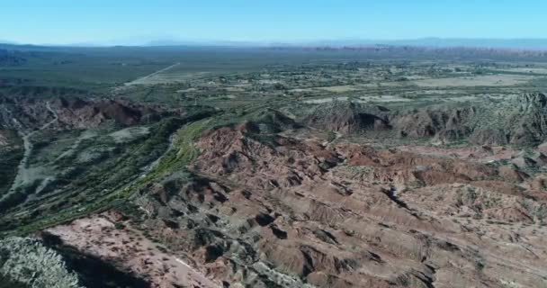 カラフルな折られた山の間の緑の Huaco 川流域の空中ドローン シーン。田舎の町および生産的な土地の背景。Huaco、サン ・ フアン州、アルゼンチン — ストック動画