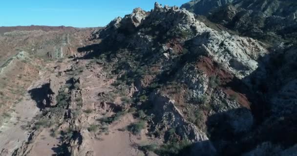 Letecká drone scéně velmi blízko letící nad barevné skalní útvary, které vznikají ze země s úhlem. Pohled shora červené a bílé kameny skládané hory. Provincie San Juan, Huaco — Stock video