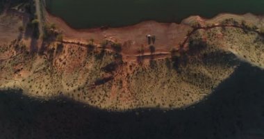 Kırmızı ve yeşil sahilde günbatımı hava dron senital sahne. Sahil göl doğru üzerinde çok yüksekten uçuyor. Sendika Villa, Rioja Eyaleti, Arjantin