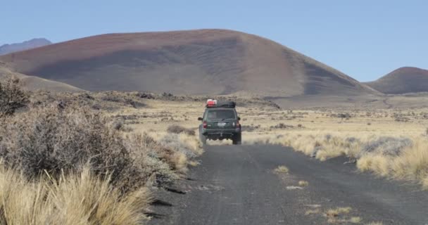 Van im Payunia Nationalpark. Vulkanzone aus Lapillis. Hintergrund des Vulkans Herradura und rote, schwarze und goldene Berge. Die Kamera bleibt stehen, während sich das Auto bewegt. Malarge, Mendoza, Argentinien — Stockvideo