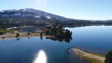 Alumine Gölü, Villa Pehuenia, Moquehue, Patagonya Arjantin hava dron sahne. Kamera Adaları arasında ileriye doğru hareket. Dağları kar ve arka planda evleri ile. Göl üzerinde sis.