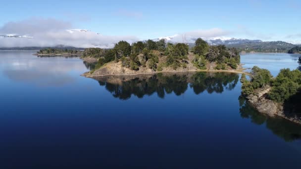 異常な湖 ヴィラ Pehuenia Moquehue ネウケン アルゼンチン パタゴニアの空中ドローン シーン カメラの移動は上下島へ転送します 雪と低い雲と山 — ストック動画