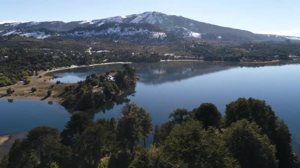 在阿根廷巴塔哥尼亚的佩韦尼亚别墅 莫克霍 诺伊肯的铝湖空中无人机场景 摄像机穿过一个岛屿到海岸 有雪和低云的山脉 — 图库视频影像