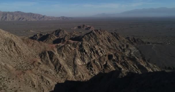 Letecká drone scéně suchý desertic hornaté krajiny. Létání nad erodované skalní útvary, široká pampa narýsované suché řek. Misty mountain řetězy na pozadí. Castelli, Rioja province, Argentina — Stock video