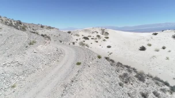 Drone антена сцена гравійної дорозі і гори із дюн та безлюдній пустелі з кілька зелених рослин. Камера рухається вперед виявлення краєвид. Taton, Катамарка провінції, Аргентина. — стокове відео