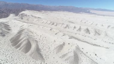 Çöl parlak açık bej kum ile hava dron sahne. Kamera hareketli arka plan üzerinde ileri keşfetmek tepeleri ve belgili tanımlık andes dağ. Taton, Catamarca Eyaleti, Arjantin.