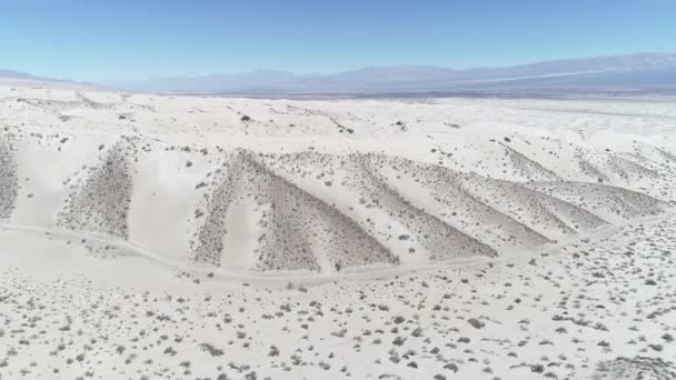 Escena aérea de drones del desierto con arena beige clara brillante. Cámara moviéndose hacia arriba descubriendo dunas y las montañas de los andes en el fondo. Taton, Provincia de Catamarca, Argentina . — Vídeo de stock