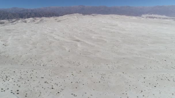 Drohnen-Szene der Wüste mit hellem, klarem beigen Sand. Die Kamera bewegt sich vorwärts und entdeckt im Hintergrund Dünen und die Berge der Anden. taton, katamarca provinz, argentinien. — Stockvideo