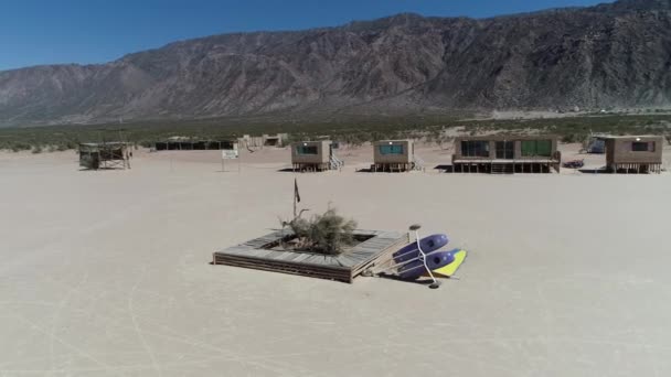Εναέριο κηφήνα σκηνή λεπτομέρεια της κλίνει πάνω από άνεμος καλάθι για αγώνες στην έρημο barreal σε aimogasta, Λα Ριόχα, Αργεντινή. Μικρά σπίτια πλίθας. Φωτογραφική μηχανή κινείται γύρω από το αυτοκίνητο και ξύλινα εγκαταλειφθεί καθίσματα . — Αρχείο Βίντεο