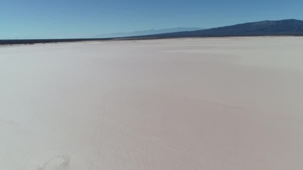 Drohnen-Szene in der Wüste von Barreal bei aimogasta, la rioja, Argentinien. Kamera nach oben und entdeckt trockene, trockene Landschaft und die Anden-Berge im Hintergrund. Autospuren auf dem Feld. — Stockvideo