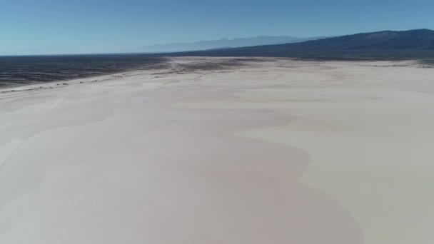 Scène aérienne de drone du désert boréal à aimogasta, la rioja, l'argentine. Caméra reculant et découvrant de petites maisons en adobe. Les montagnes andes en arrière-plan. Voiture pistes sur le terrain . — Video