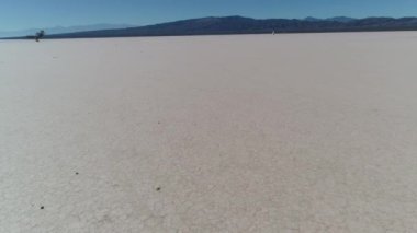 Hava dron sahne kurak kuru barreal çöl aimogasta, la rioja, Arjantin. İleri hareketli kamera boş bir arazi araba parça dolu kırık yere yakın. Arka planda dağlar.